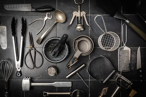 A collection of steel kitchen utensils on a granite surface